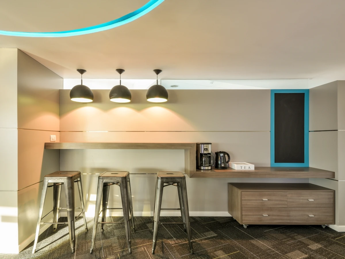 Área de café y cocina con barra y banquetas